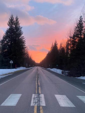 picture of a straight section of road with the sun setting at the end of the road